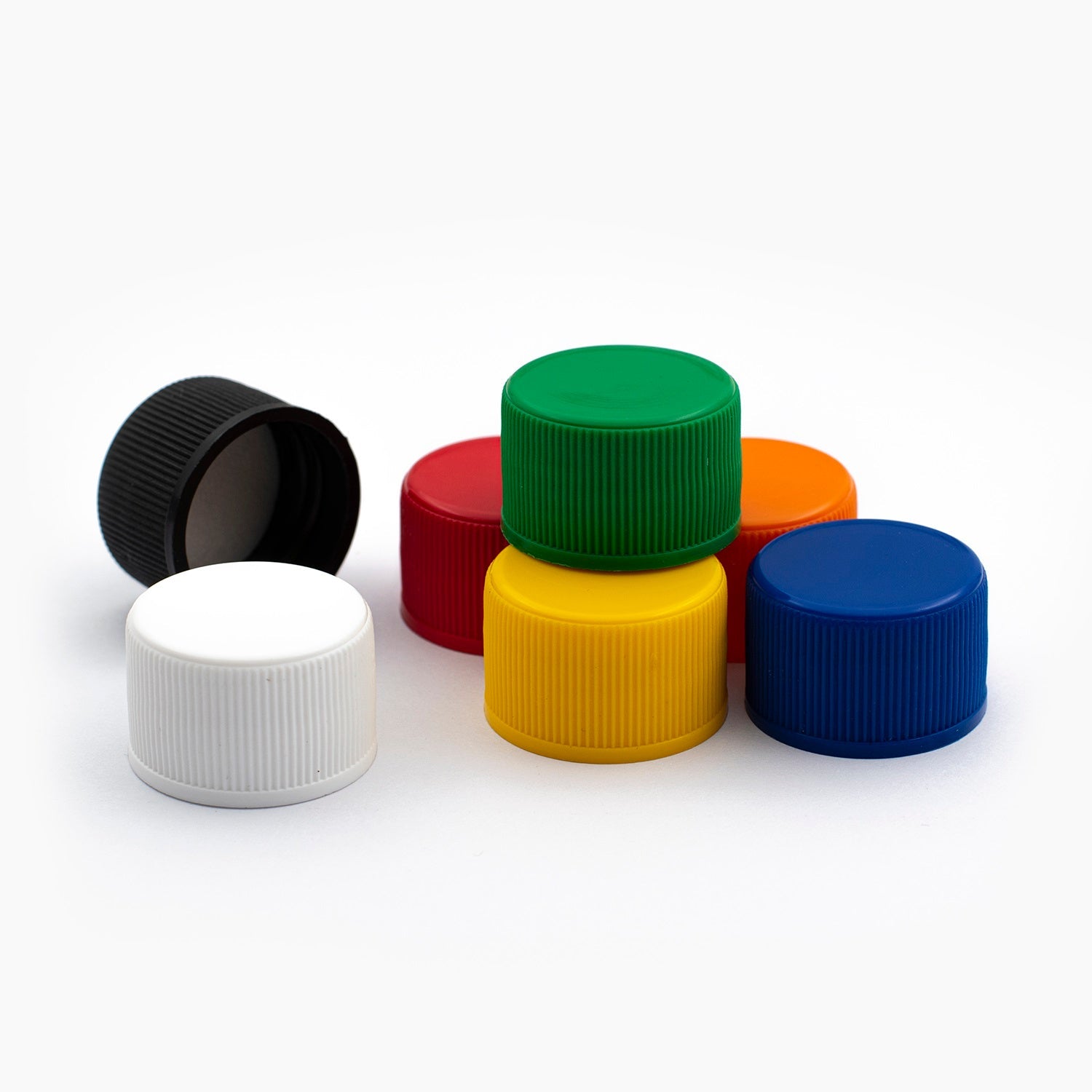 Seven 24mm Plastic Standard EPE Liner Bottle Caps Of Varying Colour On White Background | Brightpack Closures And Accessories
